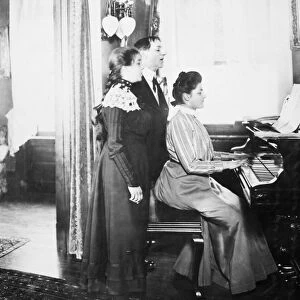 FAMILY SINGING, c1900. A turn-of-the-century New York family rehearses a tune in
