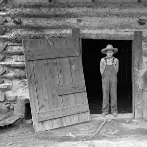 FARM BOY, 1939. A farmers son standing in the doorway of a tobacco barn in Person County