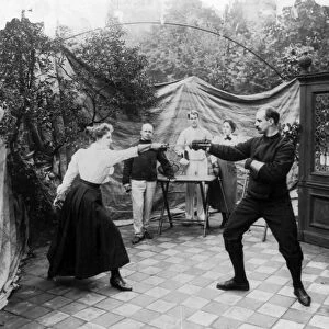 FENCING, c1904. A woman and a man dueling as three people watch. Photograph, c1904