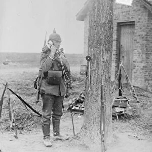 FIELD TELEPHONE, 1914. German soldier using a field telephone attached to a tree