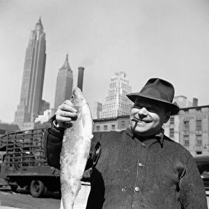 FULTON FISH MARKET, 1943. A fisherman holding a fish at the Fulton Fish Market in New York City
