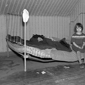 GIRL SITTING ON BED, 1936. One of Edgar Allens children sitting on the bed of his farmhouse