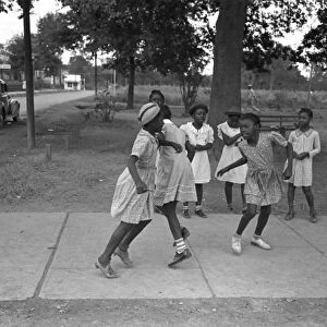 GIRLS PLAYING, 1938. A group of African American girls playing on a rural sidewalk in Lafayette