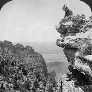 GRAND CANYON: SIGHTSEERS. A woman and a man on a cliff overlooking the Grand Canyon in Arizona