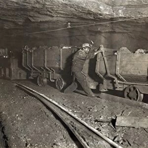 HINE: CHILD LABOR, 1908. A boy pulling the brake on a motor train filled with coal