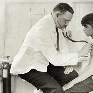 HINE: DOCTOR, 1924. A doctor examining a young worker in the infirmary at the Cheney