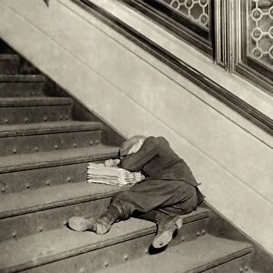 HINE: NEWSBOY, 1912. Newsboy sleeping on the stairs with newspapers at night in Jersey City