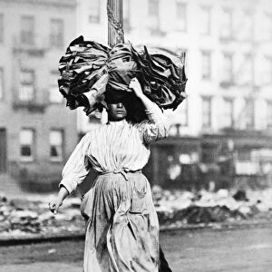 HOME INDUSTRY, 1910. Italian immigrant woman carrying cloth to her Lower East Side