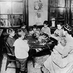 HOME INDUSTRY, 1910. A woman and her children making artificial flowers in their