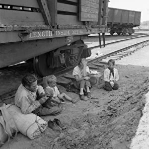 HOMELESS FAMILY, 1939. A destitute farmer with his family seated beside railroad