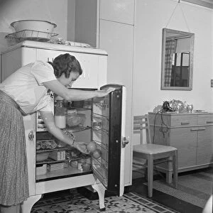 ICEBOX, 1942. A woman takes an orange out of an icebox in her in Greenbelt, Mississippi