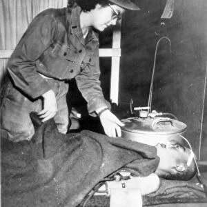 KOREAN WAR, 1952. An American Army nurse checking a Chinese communist soldier, wounded in the fighting on Whitehorse Hill, October 1952