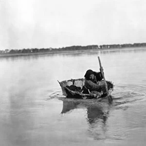 MANDAN BULL BOAT, c1908. A Mandan Native American woman paddling a bull boat
