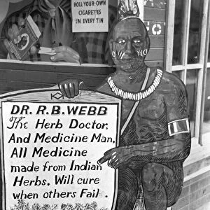 MEDICINE MAN, 1938. A Native American medicine sign advertising an herbal doctor in Pine Bluffs, Arkansas. Photograph by Russell Lee in September 1938