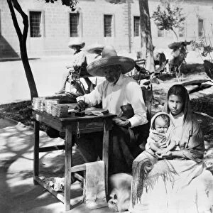MEXICO: LETTER WRITER. Public letter writer in Mexico, taking dictation from a woman holding an infant. Photograph, late 19th or early 20th century