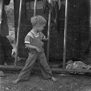 MIGRANT CHILD, 1936. Son of destitute migrant worker playing with the coils of