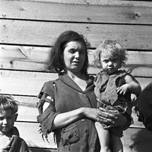 MIGRANT FAMILY, 1936. An impovished mother with two of her children at a migrant worker camp on U