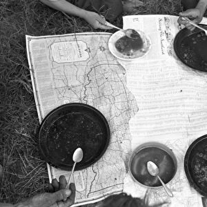 MIGRANT FAMILY, 1939. The lunch of a migrant family with a map as a tablecloth