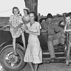 MIGRANT WORKERS, 1939. A family of migrant workers with their automobile in the Arkansas River bottoms near Vian, Oklahoma. Photograph by Russell Lee, 1939