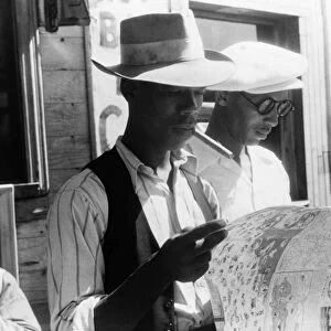 MIGRANT WORKERS, 1940. Florida migrants studying a road map before leaving Elizabeth City