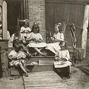 A mother with her six children working on garment tags on a tenement stoop in Roxbury, Massachusetts. Photograph by Lewis Hine, August 1912