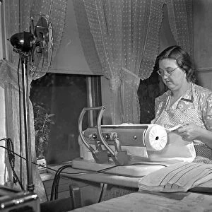 Mrs. Robert Bacon, a farm wife in Knox County, Tennessee, using electrical appliances in her home (a fan, an iron, and a radio) with power supplied by the Tennessee Valley Authority. Photographed by Arthur Rothstein, 1942