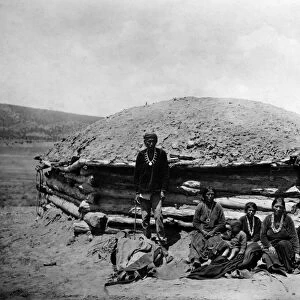 NAVAJO DWELLING, c1906. Dine Tsosi, a Navajo leader, with women and children in front of a hogan, a traditional dwelling, in the southwest United States. Photograph by Simeon Schwemberger, c1906