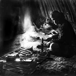 NAVAJO SILVERSMITH, c1915. A Navajo man shaping silver near a fire inside a dwelling. Photograph, c1915
