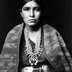 NAVAJO WOMAN, c1904. Navajo woman wearing a silver squash blossom necklace, concho belt and a blanket draped over her shoulders. Photograph by Edward Curtis, c1904
