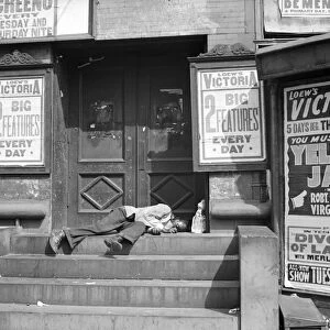 NEW YORK CITY, 1938. A man sleeping in the doorway of the Loews Victoria Theatre in Harlem