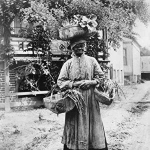 NORTH CAROLINA, c1920. A portrait of Aunt Letty carrying baskets of vegetables in New Bern