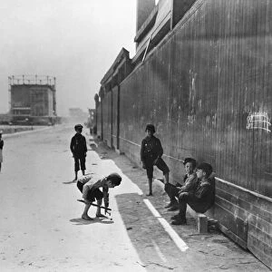 NYC: TENEMENT LIFE. Boys playing a game near tenements in New York City