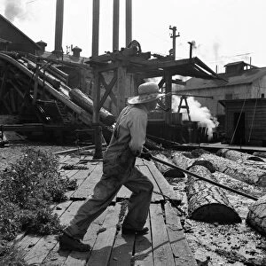 OREGON: SAW MILL, 1939. A pond monkey worker guides the direction of logs