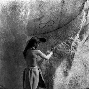 PAIUTE PAINTER, c1924. A Paiute Native American man painting on a boulder