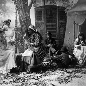 PALM READING, c1902. Staged depiction of three fashionable women having their fortunes told with cards at a Gypsy camp. Photographed c1902