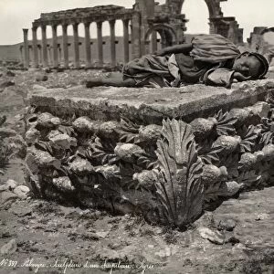 PALMYRA: RUINS. Man sleeping on a sculpted capital in front of ruins of a colonnade at Palmyra