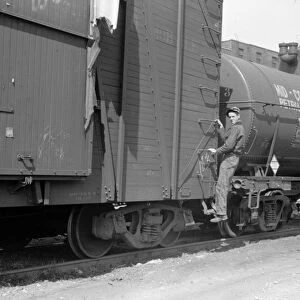 RAILROAD, 1940. A boy hopping a freight train in Dubuque, Iowa. Photograph by John Vachon