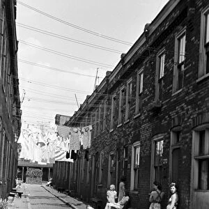 ROW HOUSES, 1938. Women and children in front of a row of low-income houses in Ambridge