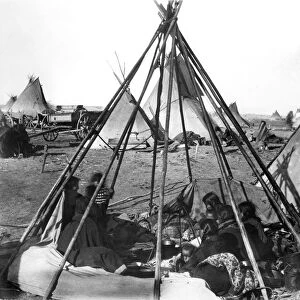 SIOUX ENCAMPMENT, 1891. Oglala Sioux women and children seated inside an uncovered tipi frame
