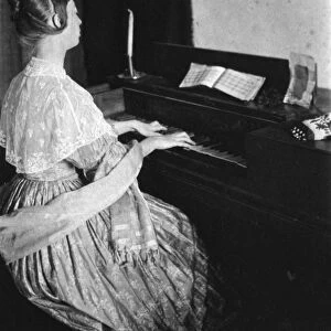 SPINET PIANO, c1900. Woman playing a spinet piano. Photographed by Frances S. Allen