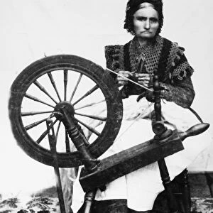SPINNING WHEEL. An American woman spinning yarn. Photograph, 19th century