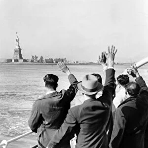 STATUE OF LIBERTY. Part of a group of illegal immigrants waving goodbye to the Statue of Liberty from the Coast Guard cutter that took them from Ellis Island to the Home Lines ship Argentina in Hoboken for deportation. Photographed by Al Ravenna, c1952