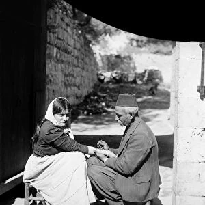 STREET TATTOO. A peasant woman receiving a tattoo on the streets of an unknown location