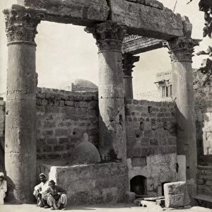 TEMPLE RUINS. Two Middle Eastern men seated in front of temple ruins