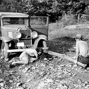 TIRE CHANGING, 1940. Photographer Marion Post Wolcott changing a flat tire on a borrowed car