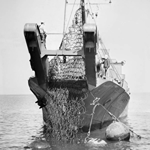 U. S. Navy mine layer ship picking up an anti-torpedo net at Norfolk, Virginia. Photographed 1945