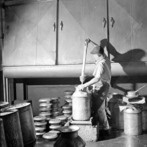 VERMONT: CREAMERY, 1941. A worker fills a milk can with cream as it exits a cooling