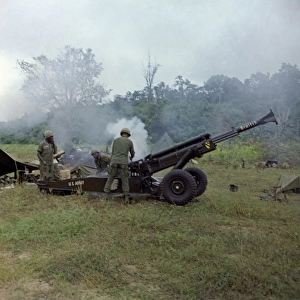VIETNAM WAR, 1966. US Army soldiers firing an M102 howitzer in the direction of Viet Cong