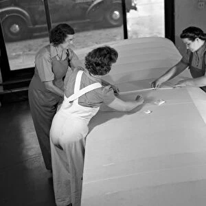 Three women sewing fabric on the wing of an airplane in De Land, Florida, during World War II. Photograph by Howard Hollem, 1942