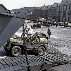 WWII: D-DAY, 1944. American jeeps loading onto a landing ship in a port town in England